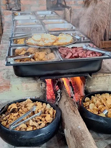 Panelas de ferro e barro no fogão a lenha aceso com comida caipira e frituras douradas