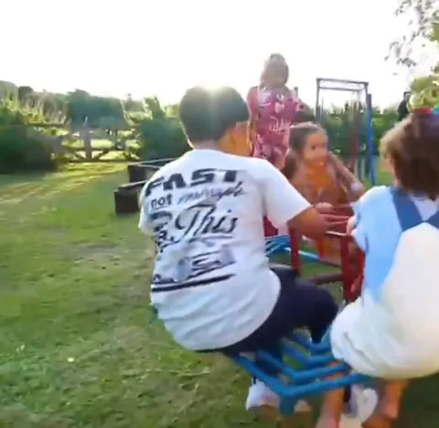 Crianças girando no gira-gira do parquinho no fim da tarde