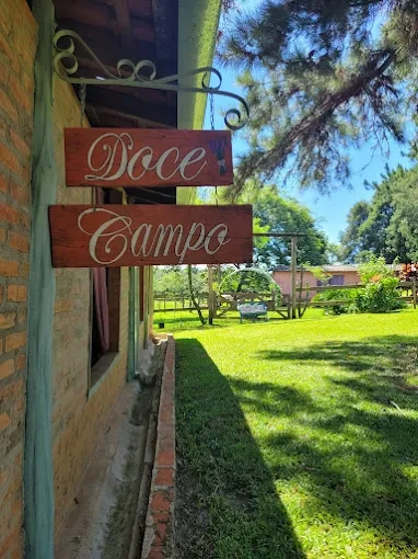 Placa rústica de madeira Doce Campo na coluna de tijolos com gramado ao fundo